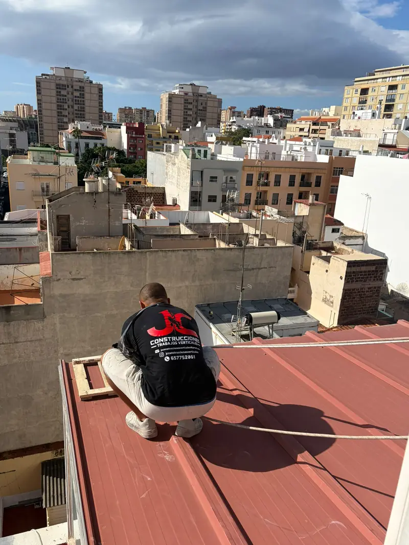 Cristofer González, de JC Construcciones, preparando las cuerdas en una azotea con la ciudad detrás