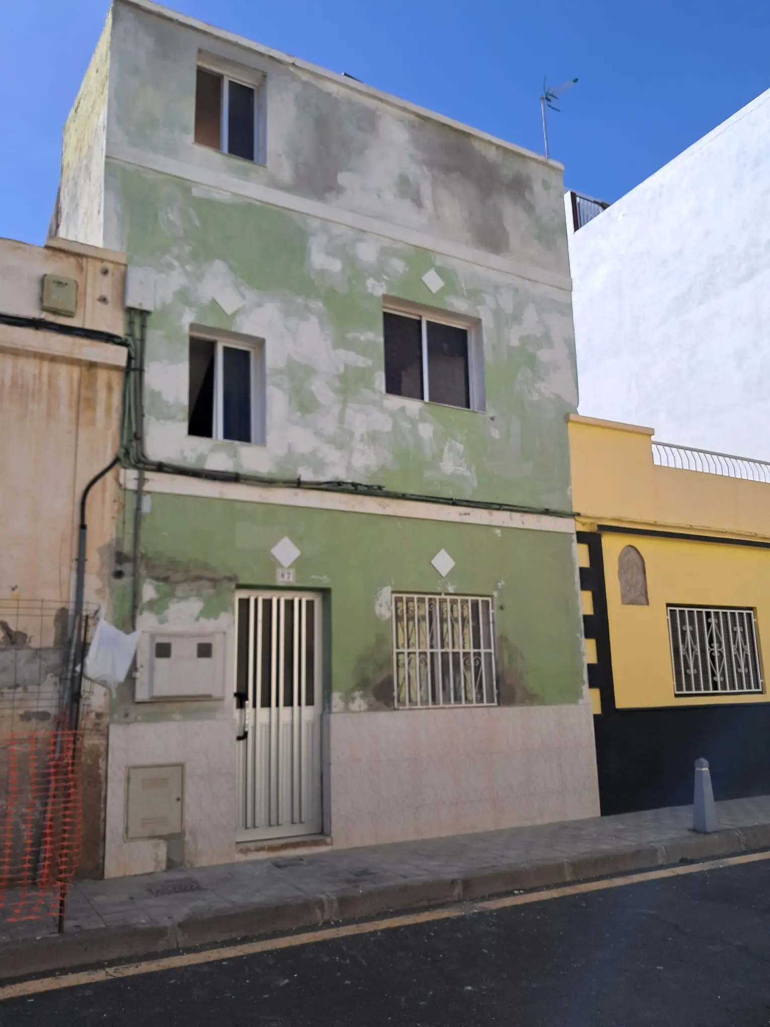 Fachada antes de la obra, con la pintura verde desconchada