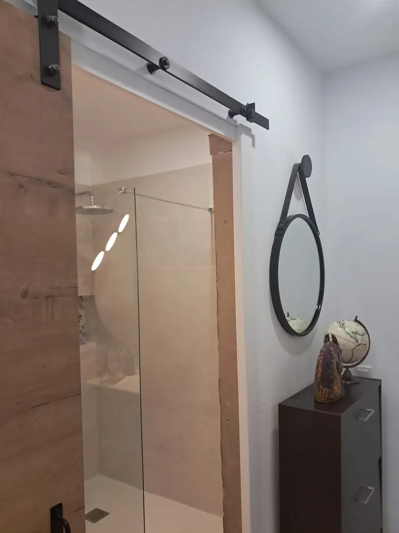 Baño reformado con ducha de obra y puerta corredera de madera